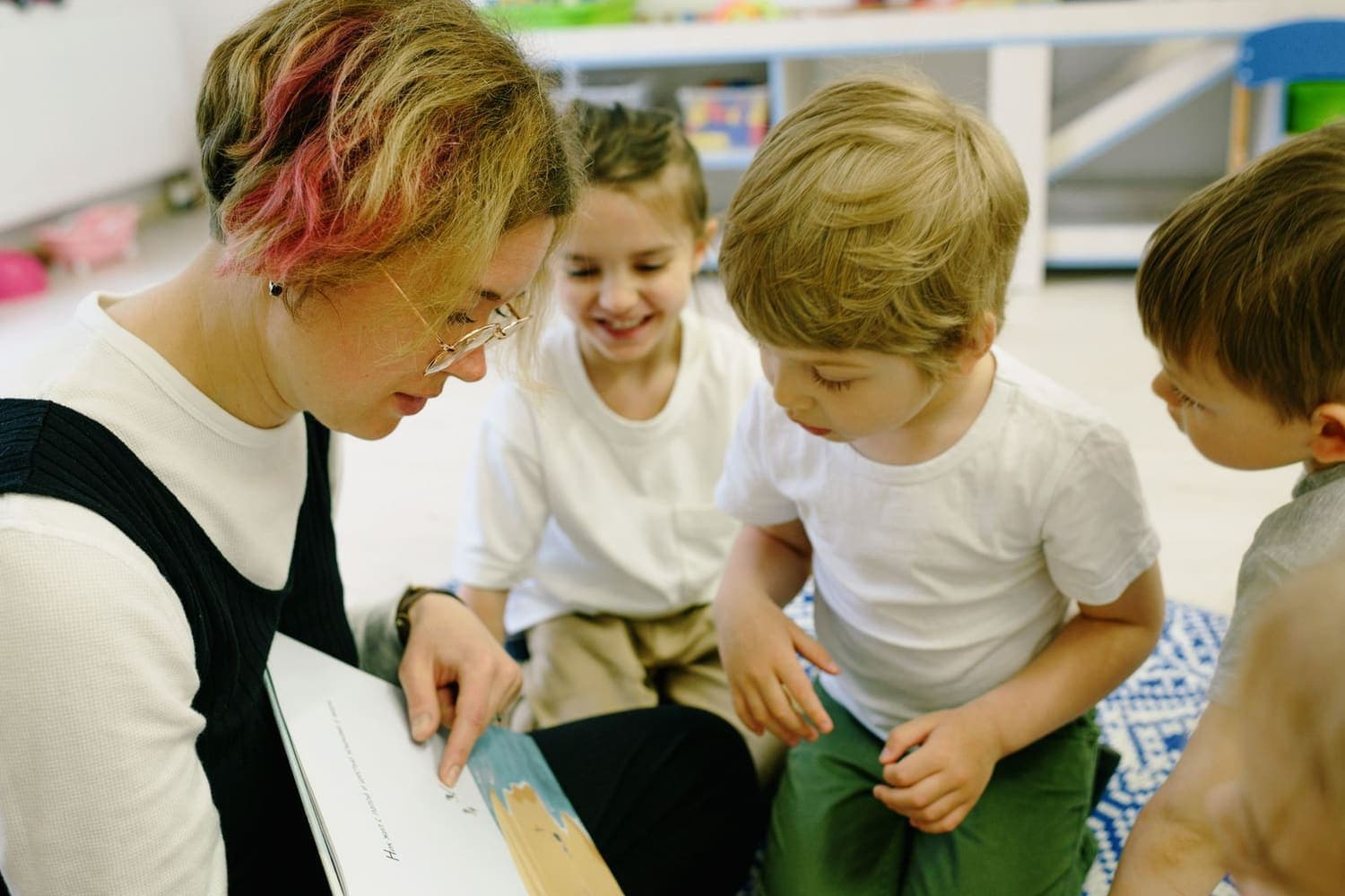 Early years practitioner reading a picture book to children in a nursery classroom